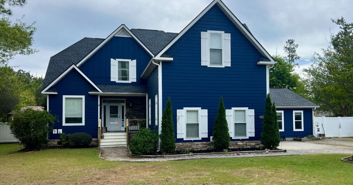 Blue two-story home with a dark architectural shingle roof under a cloudy sky