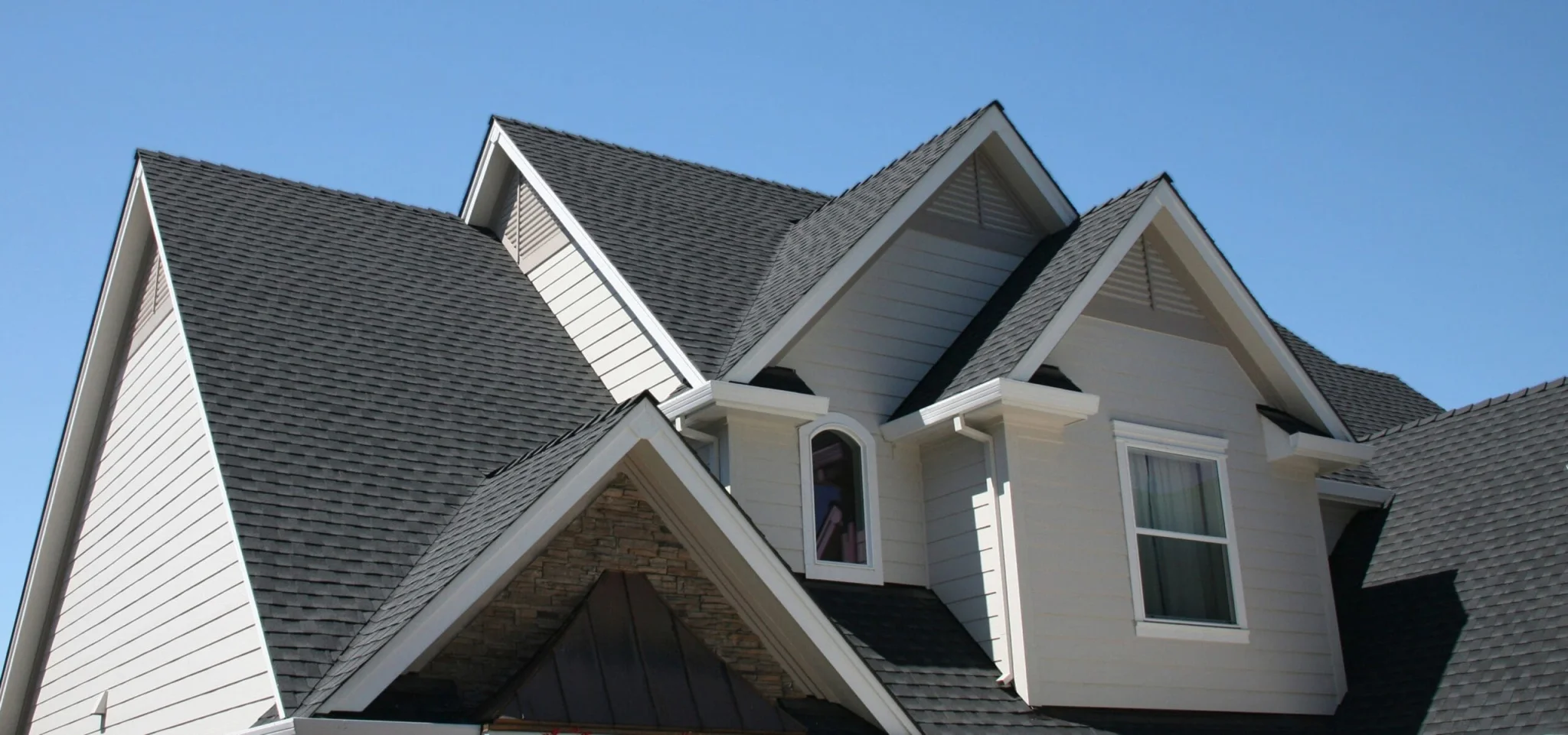 Gray asphalt shingle roof with several gables on a two-story house
